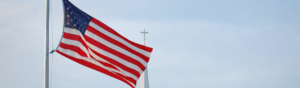 american flag in front of a steeple cross